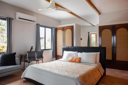 sypialnia z łóżkiem, krzesłem i oknami w obiekcie La Perla del Caribe - Villa Sapphire w mieście San Pedro