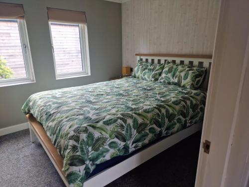 una camera da letto con un letto con un piumone verde e due finestre di Derwen 2 Bedroom Luxury Lodge a Welshpool