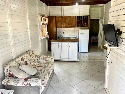 a kitchen with a couch and a tv in a room at Cabana com piscina - 5 min a pé da praia - Porto Belo in Porto Belo