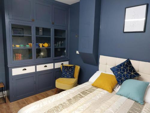 a blue bedroom with a bed and a yellow chair at spacious self-contained accommodation 135 cantebury road in Kent
