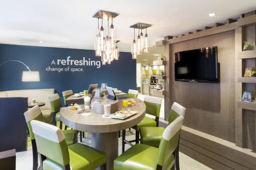 a dining room with a table and green chairs at EVEN Hotel Norwalk by IHG in Norwalk