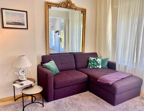 a purple couch in a living room with a mirror at Ferienwohnung Louise 50 m zum See in Kressbronn am Bodensee
