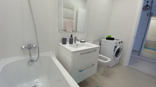 a white bathroom with a sink and a washing machine at Lovely Sunrise in Bucharest