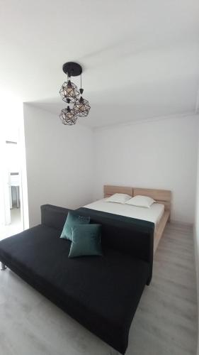 a black bed in a white room with a chandelier at Lovely Sunrise in Bucharest
