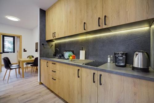 a kitchen with wooden cabinets and a counter top at Jaśmin Apartamenty in Krynica Zdrój
