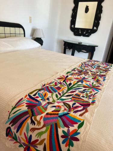 a bed with a colorful blanket on top of it at Agua Azul la Villa in Santa Cruz Huatulco