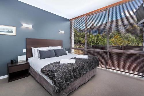 1 dormitorio con cama grande y ventana grande en Luxury 1 Bedroom Studio, en Queenstown