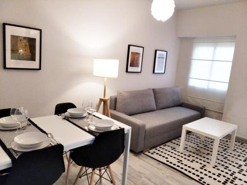 ein Wohnzimmer mit einem Sofa, einem Tisch und Stühlen in der Unterkunft Tranquilo apartamento de dos dormitorios en pleno centro in Plasencia