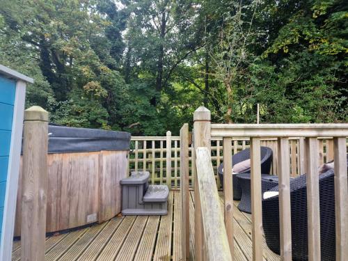 una terraza de madera con bañera de hidromasaje y parque infantil en Glamping Hut - Riverside 2, en Welshpool