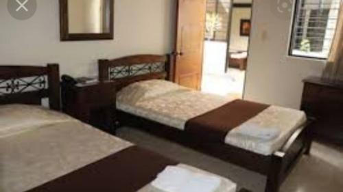 une chambre avec deux lits et un miroir dans l'établissement Hotel Baroee, à Popayan