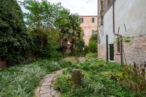 un giardino con sentiero in pietra accanto a un edificio di Angelo Raffaele incantevole casa per 12 persone a Venezia