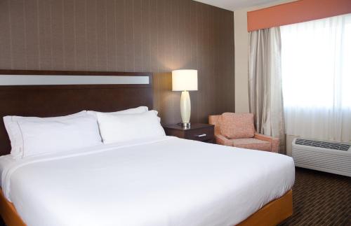 a hotel room with a large bed and a chair at Holiday Inn Express Hotel & Suites Watertown - Thousand Islands by IHG in Watertown