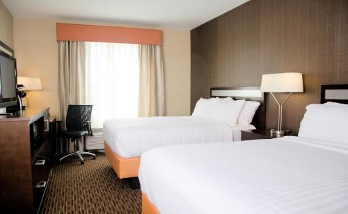 a hotel room with two beds and a television at Holiday Inn Express Hotel & Suites Watertown - Thousand Islands by IHG in Watertown