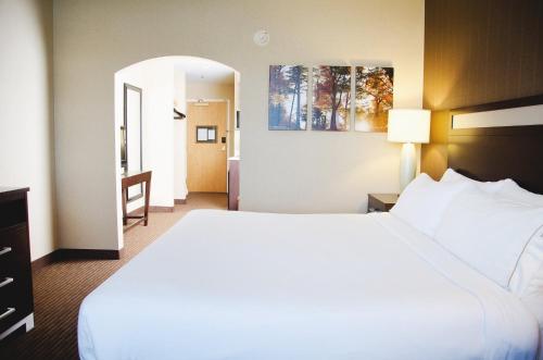 a hotel room with a large bed and a hallway at Holiday Inn Express Hotel & Suites Watertown - Thousand Islands by IHG in Watertown
