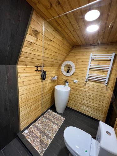 a bathroom with a toilet in a wooden wall at Eco cottage Kazbegi in Stepantsminda