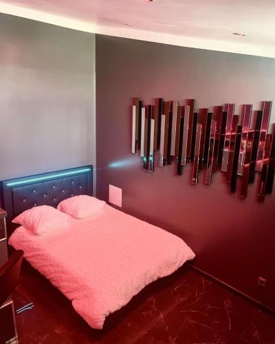 Un dormitorio con una cama rosa y una pared con obras de arte en Obalispa, en Liancourt