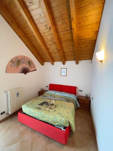 Un dormitorio con una cama roja en una habitación con techos de madera. en Attico sul Rosa en Ceppo Morelli