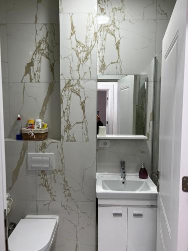 uma casa de banho branca com um lavatório e um espelho em Blini Exclusive em Pristina