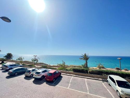 una fila di auto parcheggiate in un parcheggio vicino all'oceano di The Symphony of the Breeze a Netanya