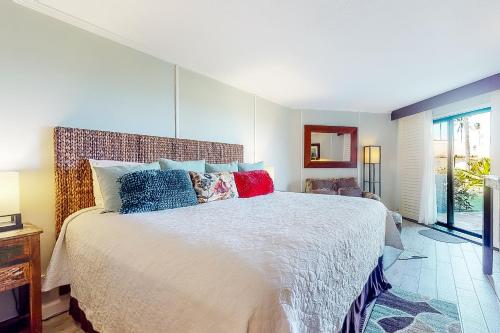 a bedroom with a large bed with colorful pillows at Kauai Beach Resort #3124 in Lihue