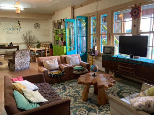 a living room with couches and a flat screen tv at Bichon La Casa Hostal in Pichilemu