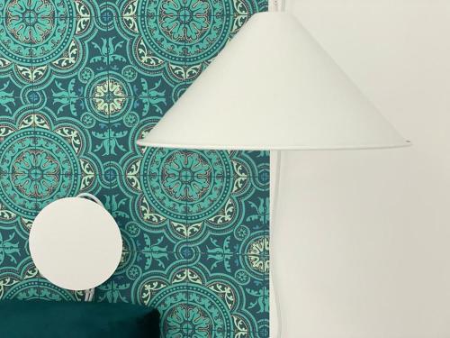 a lamp and a wall with a blue and green wallpaper at Tecnopolo Fiera Suite in Bologna