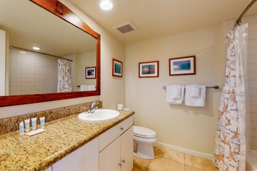 een badkamer met een wastafel, een toilet en een spiegel bij Islander on the Beach 353 in Kapaa