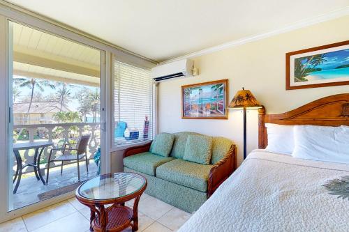 a bedroom with a bed and a couch and a table at Islander on the Beach 339 in Kapaa