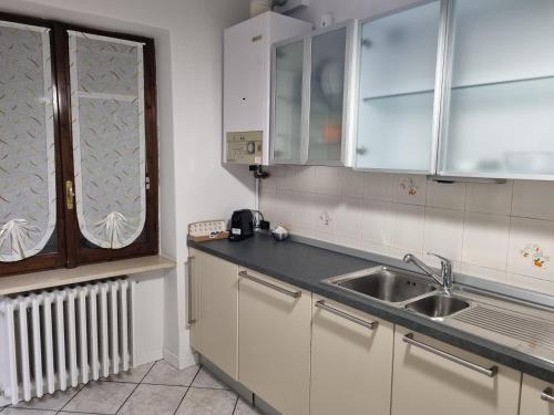 eine Küche mit weißen Schränken, einem Waschbecken und einem Fenster in der Unterkunft SWEET HOME in Azzano San Paolo