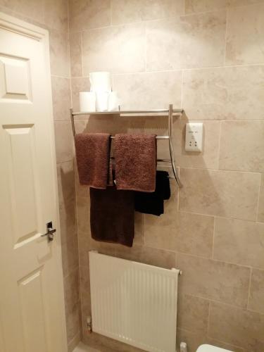 La salle de bains est pourvue de serviettes accrochées au mur. dans l'établissement 59 Halstead - Gorgeous single bedroom with private bathroom, à Halstead