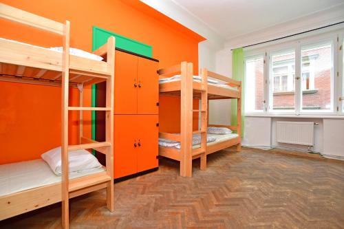 Zimmer mit 2 Etagenbetten und einer orangefarbenen Wand in der Unterkunft Prague Old Town Hostel in Prag