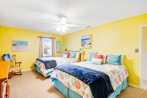 2 łóżka w pokoju z żółtymi ścianami w obiekcie Marigold Cottage w mieście Tybee Island
