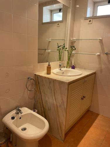 a bathroom with a sink and a toilet and a mirror at Cabanas Acqua Golden in Cabanas de Tavira