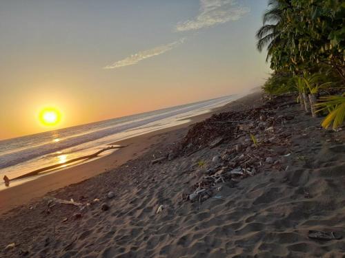 a beach with the sun setting over the ocean at HOSPEDAJE DOÑA NEL in El Valle