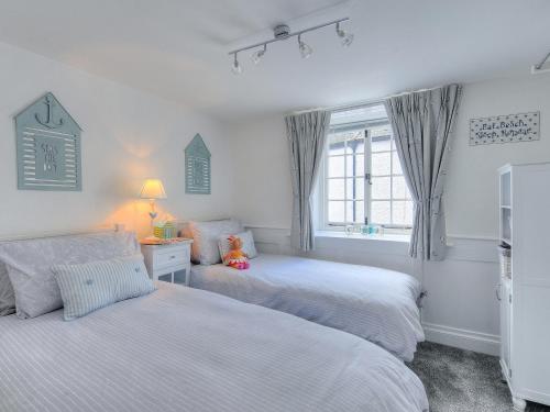 a bedroom with two beds and a window at Watersplash Cottage in Lyme Regis
