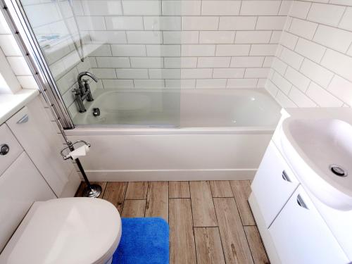 a bathroom with a white tub and a toilet and a sink at Watersplash Cottage in Lyme Regis