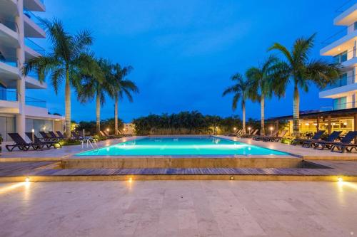 una piscina con palmeras y un edificio en Cartagena, APARTAMENTO EN EDIFICIO CON SALIDA A LA PLAYA, en Cartagena de Indias