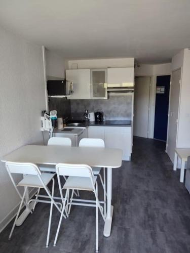 une cuisine avec une table et des chaises dans une pièce dans l'établissement Beau studio lumineux climatisé Classé 2 Etoiles, à 130 m des plages, à La Grande Motte