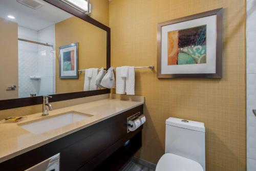 La salle de bains est pourvue d'un lavabo, de toilettes et d'un miroir. dans l'établissement Best Western Plus Chateau Fort St. John, à Fort Saint John