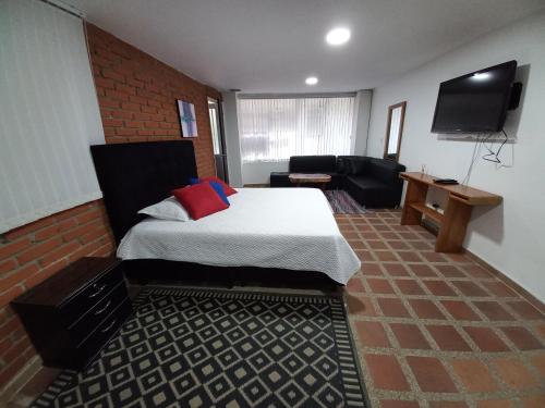 a bedroom with a bed and a couch and a television at Apartamento amoblado en la Francia in Manizales