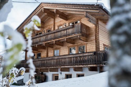 a wooden house with a balcony in the snow at Oberschupferhof in Außervillgraten
