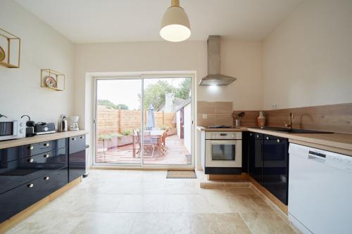 a kitchen with blue cabinets and a view of a patio at VILLA SANDERLING au cœur de Saint Valery Haut standing 5 étoiles in Saint-Valéry-sur-Somme