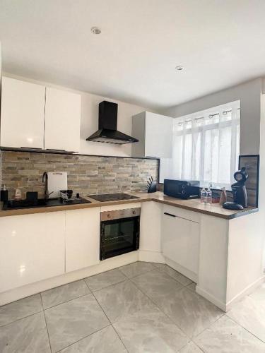 une cuisine avec des armoires blanches et un four à plaques de cuisson dans l'établissement GRAND T2 GARE AMIENS TOUT CONFORT 2PERS WIFI, à Amiens