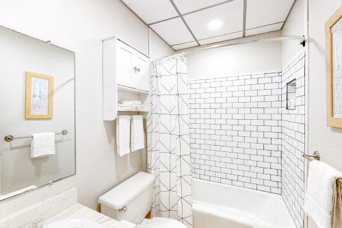 a white bathroom with a toilet and a shower at Unit 32, Island Retreat Resort in Port Aransas