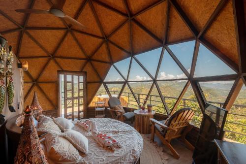 een kamer met een bed in een grote kamer met een groot raam bij La Colina Glamping in La Vega