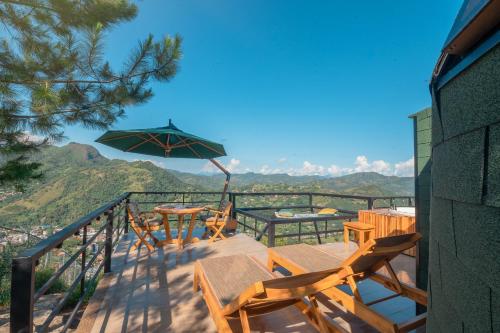 a balcony with tables and chairs and an umbrella at La Colina Glamping in La Vega
