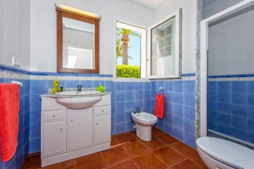 a blue tiled bathroom with a sink and a toilet at Villa Ondinas by Villa Plus in Cala en Forcat