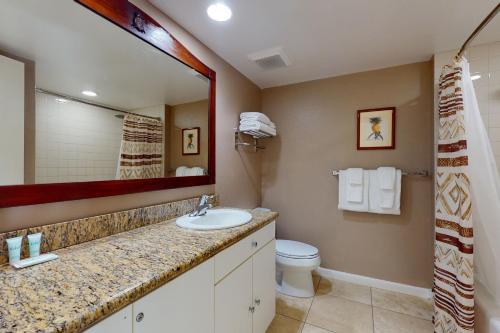 a bathroom with a sink and a toilet and a mirror at Islander on the Beach 211 in Kapaa