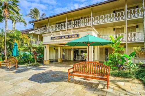 a bench with an umbrella in front of a hotel at Islander on the Beach 354 in Kapaa