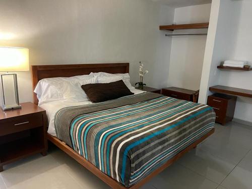 a bedroom with a bed with a colorful striped blanket at Hotel Suites del Mar in Palmas